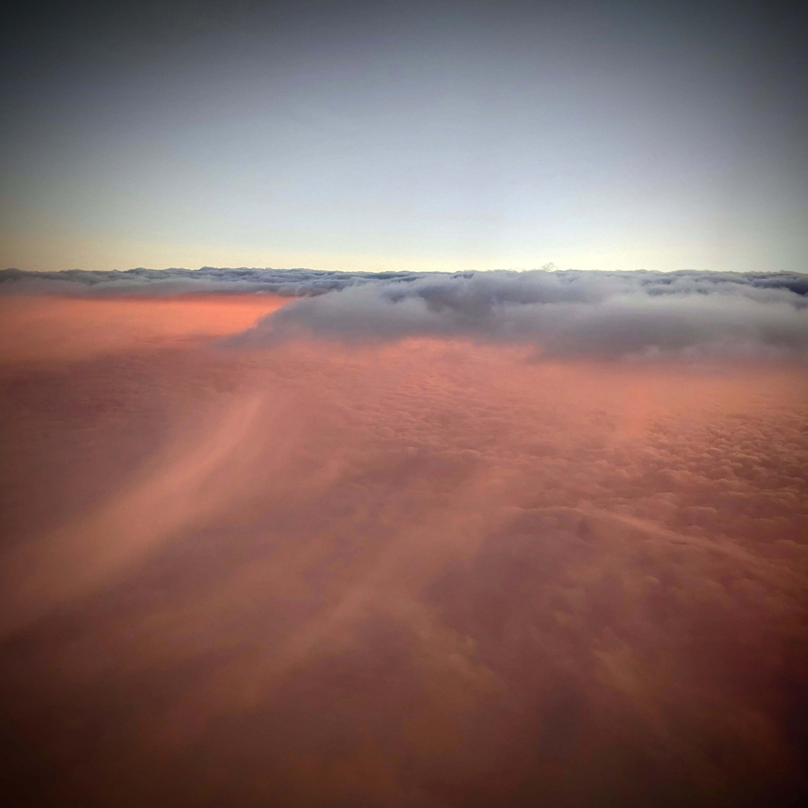 Rose-tinted clouds at dawn viewed from above
